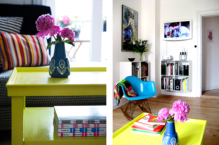 Detalje af gult sofabord med vase og blomster samt fladskærms TV