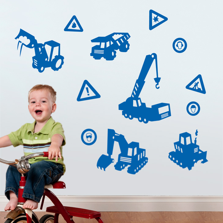 Boy on a 3 wheeled bike in fornt of a white wall with blue wallstickers in silhouette with different machines from a construction site. A dumper, a digger, a crane, a bulldozer and different warning signs.