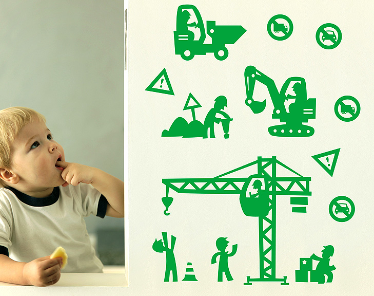 Boy sitting and eating an apple next to a wall with green wallstickers. The wallstickers are drawn in silhouet in a comic style. There is a small dumper, a man sitting in acrane, a mand shoutning up to the crane, a man sitting on some boxes, a man with a jackhammer.